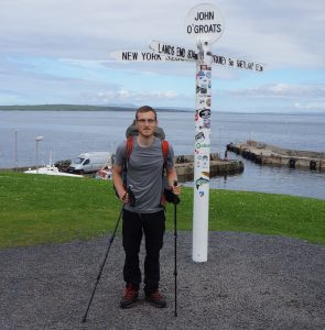 Justin standing by signpost at John o'Groats